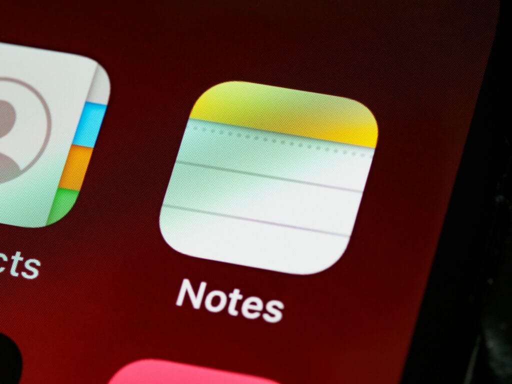 화면 너머로 보이는 iOS 내장 노트 앱 아이콘.